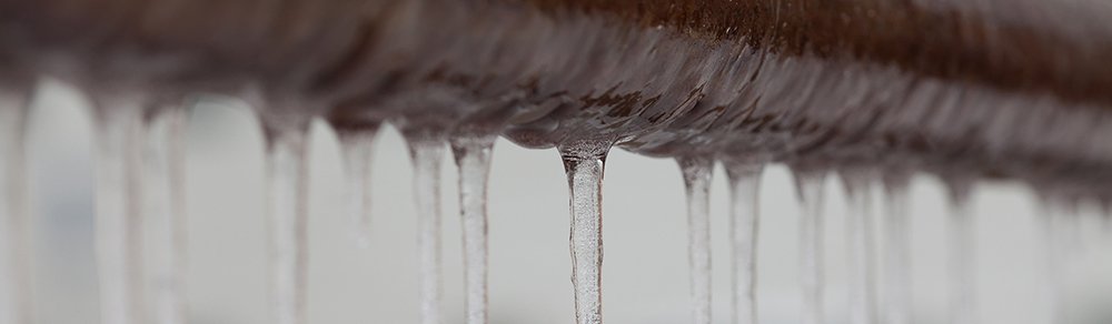 Icicles hanging from a brown frozen pipe